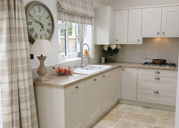 This pale stone kitchen flooring perfectly complements the neutral shade of the solid wood kitchen cabinets.