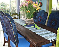 A dining table with a Mexican style runner, decorative plates and a bunch of colourful flowers