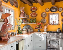 A Mexican kitchen style with bright yellow walls, decorative plates and light cabinetry