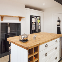 A monochrome kitchen with a double fridge-freezer, wood burning stove and an island featuring a wine fridge