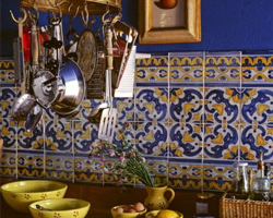 A Mexican kitchen style with deep blue walls, a tiled splashback and a hanging utensil rack
