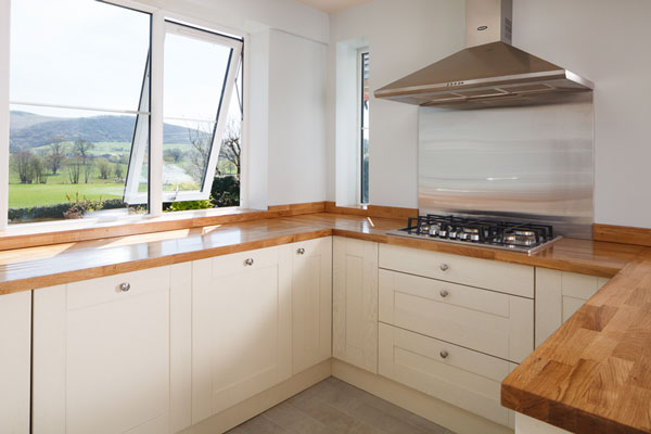 A large bright kitchen with a wooden worktop and open window