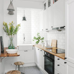 The sink positioned at the end of the kitchen and maximised use of vertical space allow room for a small seating area in this galley kitchen design