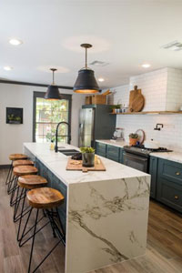 A stylish kitchen with a large marble waterfall island and wooden bar stools