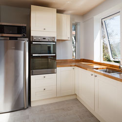 A cream and wood kitchen with stainless steel appliances