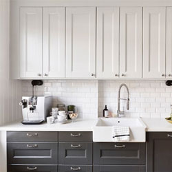 A modern kitchen with black base cabinets and white wall cabinets