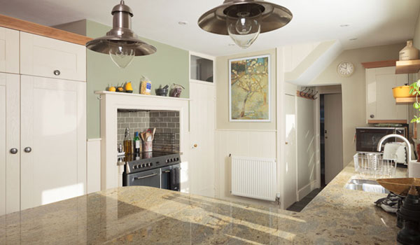 A traditional kitchen with a marble worktop, pendant lamps and white cabinets