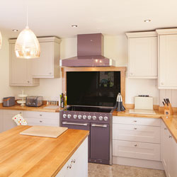 A kitchen with neutral tones, gold pendant lights and a purple oven