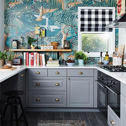 Neutral grey cabinets and a white worktop contrast with a vivid wallpaper with natural themes.