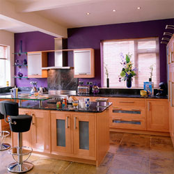 A modern kitchen with wooden cabinets and a purple feature wall