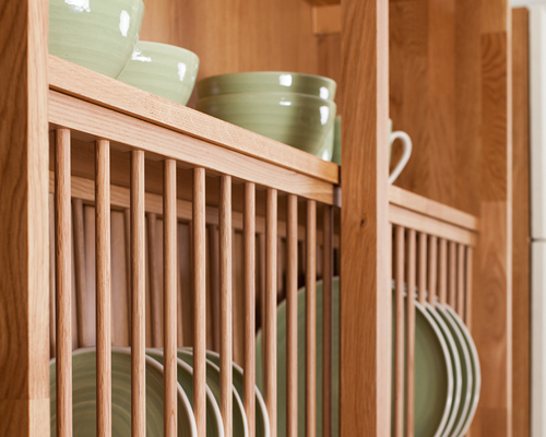 Solid oak plate rack with plates in and a shelf above for bowls.