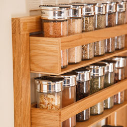 A wooden spice rack with full spice jars