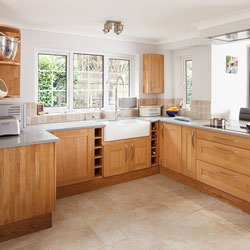 A spacious wooden kitchen with white worktop, Belfast sink and breakfast bar