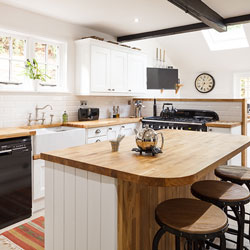 A kitchen with white cupboards, wood worktops and contemporary features