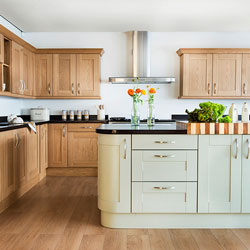 Wooden kitchen cabinets with a black worktop, and a green painted island