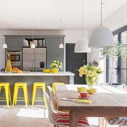 A modern grey kitchen with bright yellow barstools and accessories