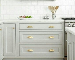 A combination of gold handles, pale grey frontals and white tiles make this kitchen feel light and airy.