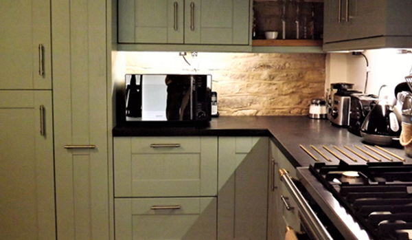 The dark colour worktop of this kitchen complements the light cabinets.