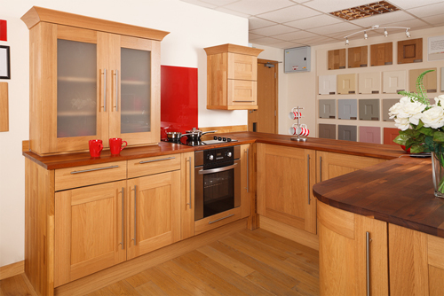 A lacquered oak kitchen with shaker frontals and a glossy red splashback.