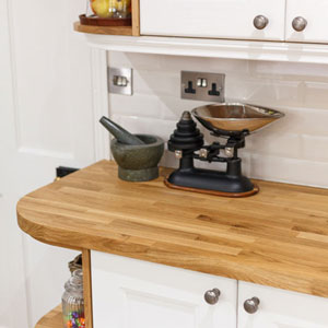 A white kitchen, open end cupboards and ornaments on a wooden worktop