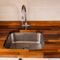 These walnut worktops are kept clear of clutter thanks to the useful addition of wooden wall cabinets